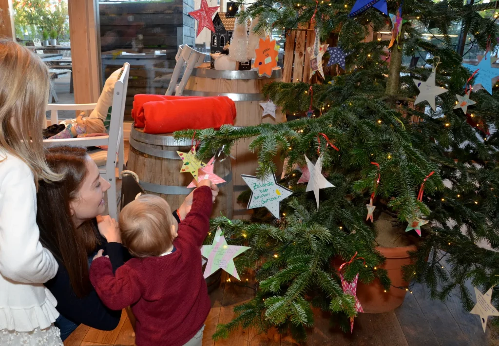 Kinder behängen den Wunschbaum auf dem Krewelshof mit Ihrem Wunschstern.