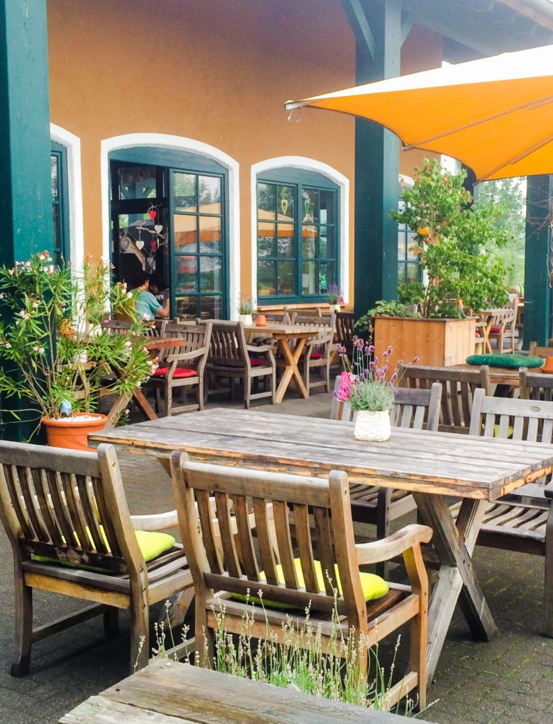 Gemütliche Holzgarnituren und sommerliche Bepflanzung auf der Restaurant-Terrasse des Krewelshof Lohmar.
